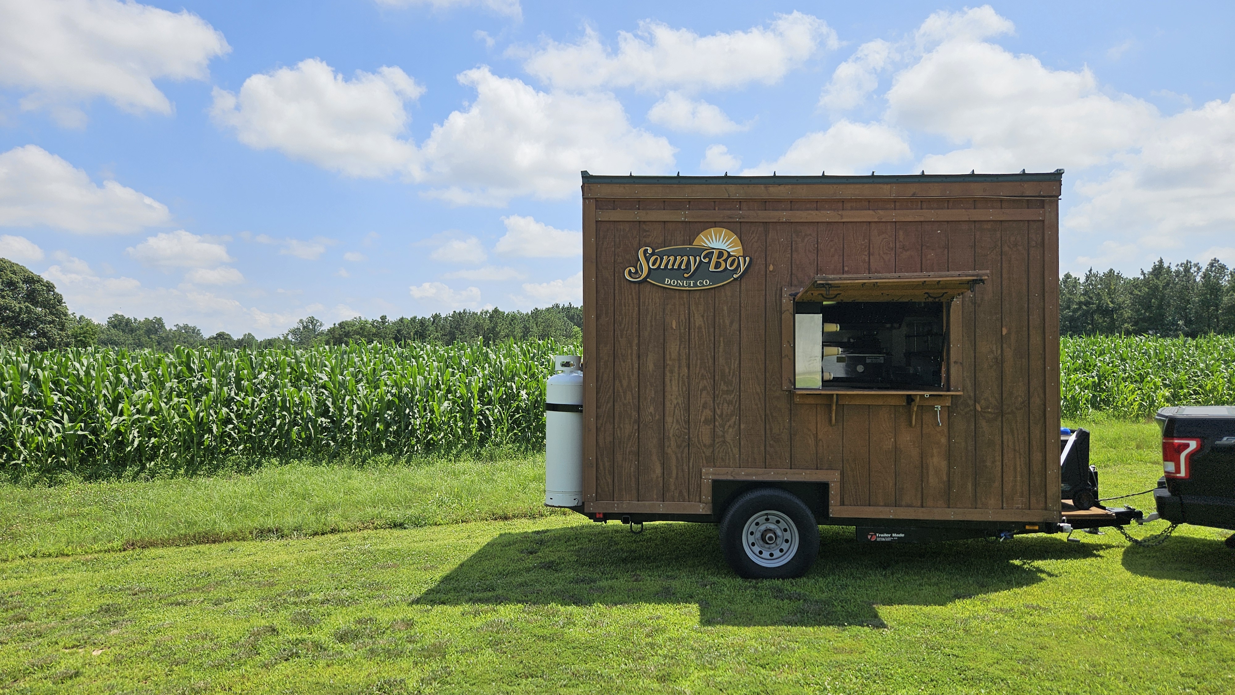 The Sonny Boy Donut Co. wooden trailer open at a summer event